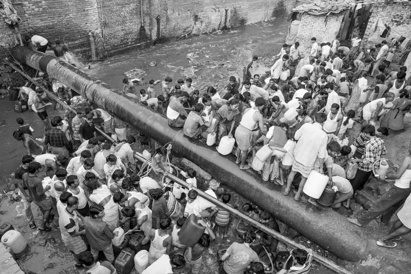 Human Right to Water in Delhi - Rush for water collection at a pipeline leakage  situated across a wastewater drain near a cluster of slum and unauthorized colonies in Delhi